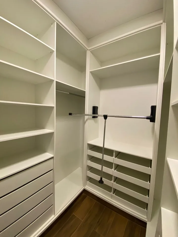 Closet planejado em MDF branco com prateleiras, gaveteiro, cabideiro central e sapateira, piso em porcelanato amadeirado