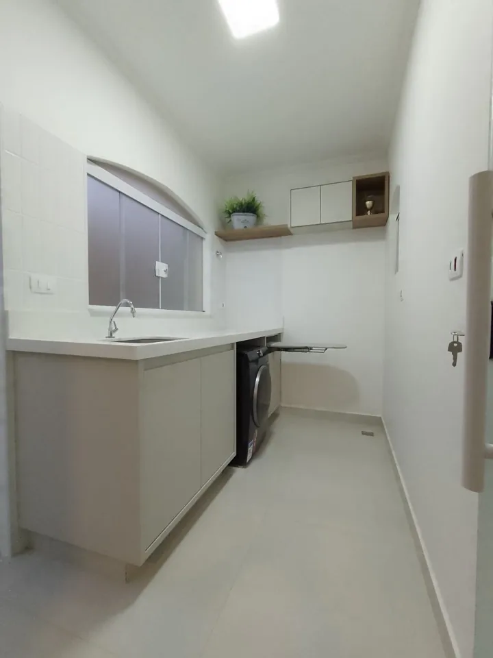 Lavanderia planejada em MDF branco com bancada de cuba, armário aéreo e tábua de passar retrátil