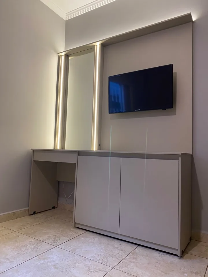 Penteadeira planejada completa com espelho iluminado, TV embutida e cômoda branca de porta lisa