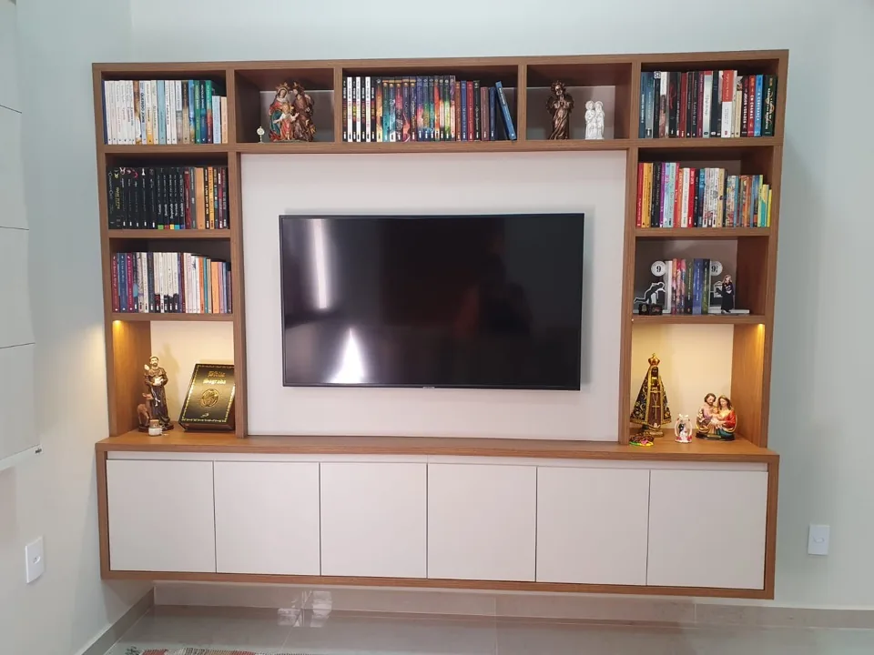Estante planejada em MDF amadeirado do piso ao teto com painel para TV e nichos para livros