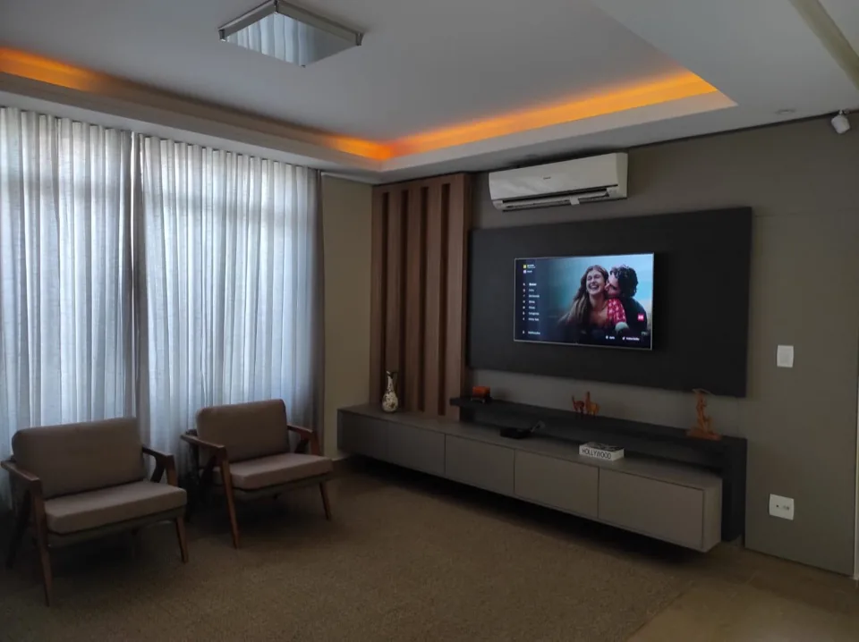 Sala de estar com painel de TV em MDF grafite, ripado de madeira e poltronas estofadas